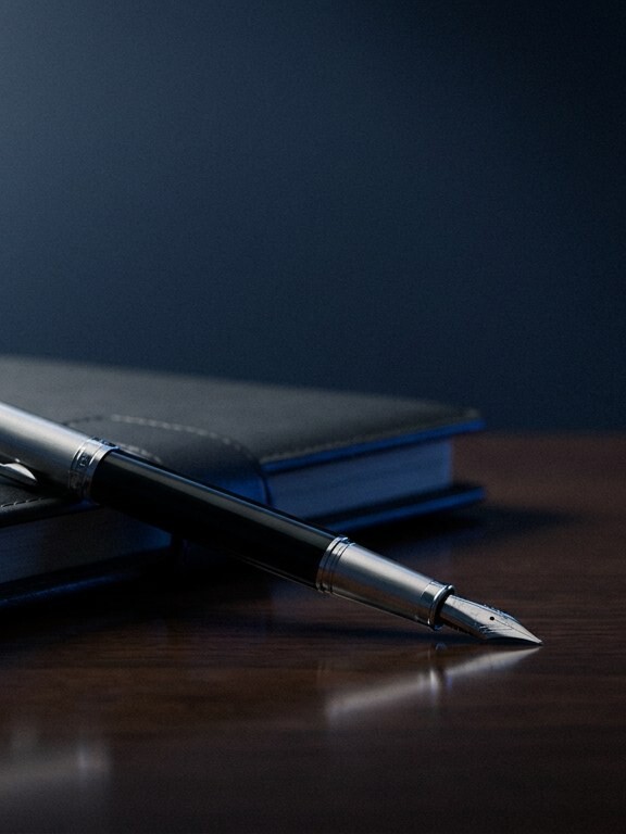 Silver fountain pen resting on a leather planner