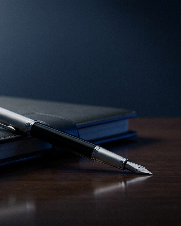 Silver fountain pen resting on a leather planner