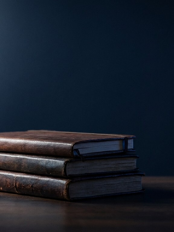 Hourglass beside a stack of leather-bound journals