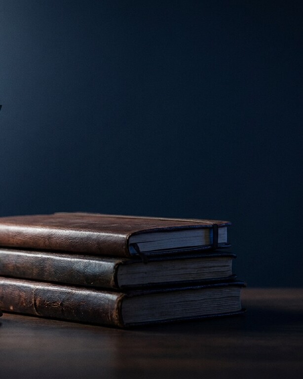 Hourglass beside a stack of leather-bound journals